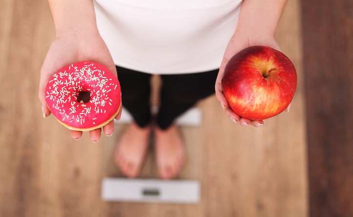 a-woman-holding-an-apple-and-a-doughnut-image